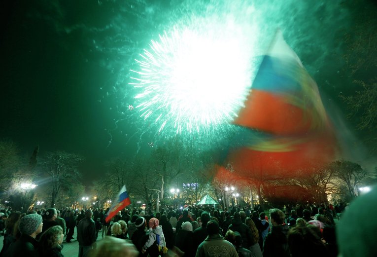 Люди наблюдают за праздничным салютом в честь присоединения Крыма к Российской Федерации на главной площади Симферополя Люди наблюдают за праздничным салютом в честь присоединения Крыма к Российской Федерации на главной площади Симферополя