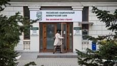 Женщина входит в здание Российского национального коммерческого банка в городе Севастополе Женщина входит в здание Российского национального коммерческого банка в городе Севастополе