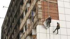 Рабочие снимают для ремонта обшивку с Дома Печати в центре города Грозного Рабочие снимают для ремонта обшивку с Дома Печати в центре города Грозного