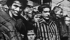 Заключенные за колючей проволокой в концентрационном лагере Освенцим Заключенные за колючей проволокой в концентрационном лагере Освенцим