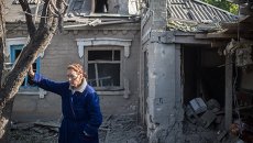 Женщина у поврежденного в результате обстрела дома в поселке Александровка. Архивное фото Женщина у поврежденного в результате обстрела дома в поселке Александровка. Архивное фото
