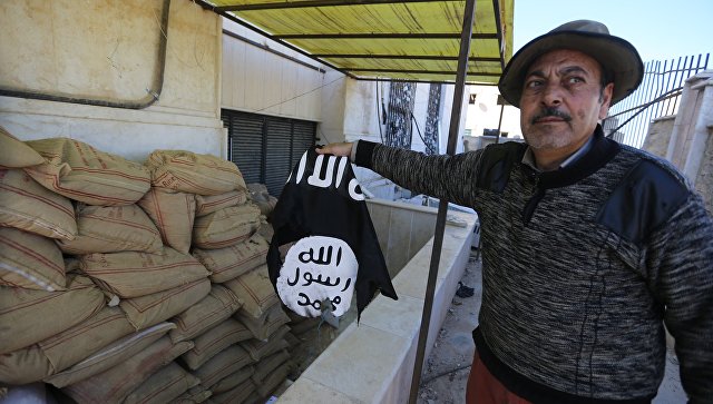 Житель Сирии держит флаг группировки Исламское государство. Архивное фото