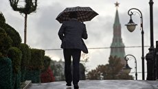 Мужчина на Лужковом мосту во время дождя в Москве. Архивное фото Мужчина на Лужковом мосту во время дождя в Москве. Архивное фото