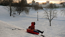 Ребенок катается с горы на берегу Большого Новодевичьего пруда в Москве. Архивное фото Ребенок катается с горы на берегу Большого Новодевичьего пруда в Москве. Архивное фото