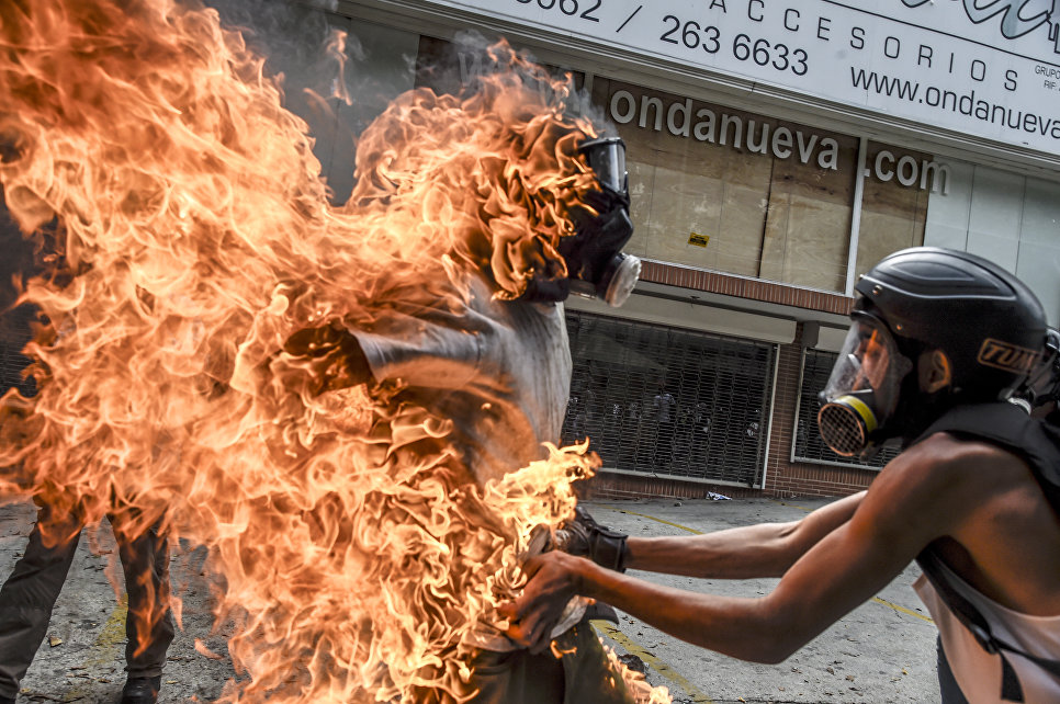 Демонстратор после взрыва бензобака полицейского мотоцикла во время столкновений в знак протеста против президента Венесуэлы Николаса Мадуро в Каракасе, 3 мая 2017