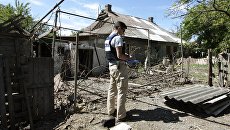 Сотрудник ОБСЕ осматривает двор жилого дома, пострадавший в результате обстрела Докучаевска в Донецкой области. Архивное фото Сотрудник ОБСЕ осматривает двор жилого дома, пострадавший в результате обстрела Докучаевска в Донецкой области. Архивное фото