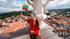 Девушка позирует с флагом Литвы на фоне Вильнюса. Архивное фото Девушка позирует с флагом Литвы на фоне Вильнюса. Архивное фото