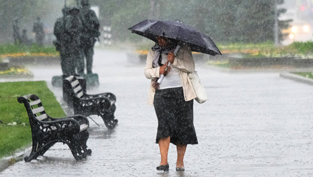 Женщина идет по Фрунзенской набережной в Москве во время дождя