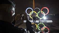 Туристы фотографируются на фоне Олимпийских Колец в Париже Туристы фотографируются на фоне Олимпийских Колец в Париже