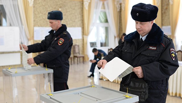Сотрудники полиции опускают бюллетени в урны на выборах президента РФ на избирательном участке в Бахчисарае