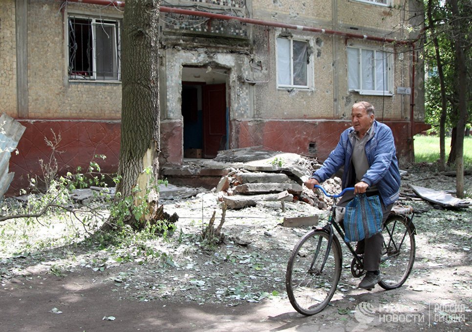 Мужчина едет на велосипеде во дворе жилого дома, пострадавшего в результате обстрела, в поселке Горловка Донецкой области Мужчина едет на велосипеде во дворе жилого дома, пострадавшего в результате обстрела, в поселке Горловка Донецкой области