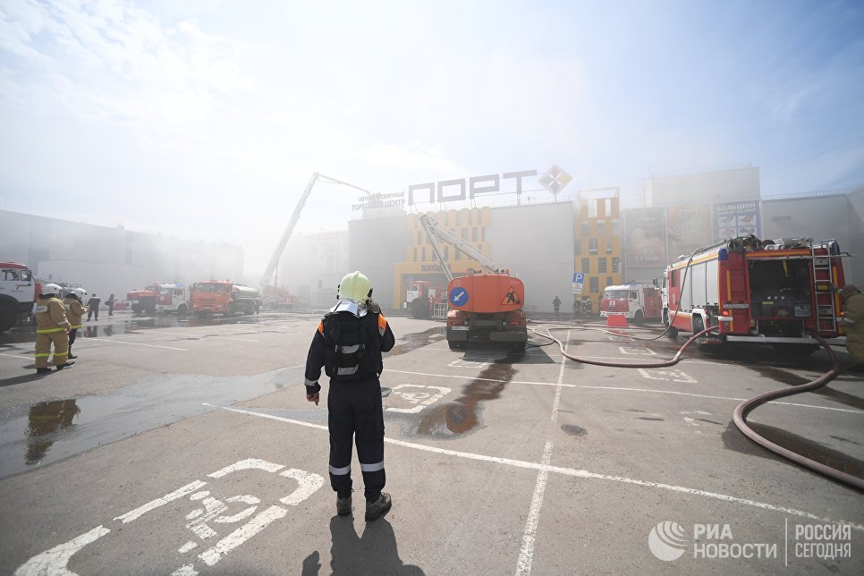 Сотрудники МЧС и пожарная техника перед зданием торгового центра Порт в Казани, где произошло возгорание