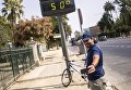 Мужчина фотографируется у электронного табло, которое показывает температуру +50 градусов по Цельсию на улицах города Севилья в Испании Мужчина фотографируется у электронного табло, которое показывает температуру +50 градусов по Цельсию на улицах города Севилья в Испании