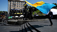Мужчина с украинским флагом у памятника основателям Киева на площади Независимости Мужчина с украинским флагом у памятника основателям Киева на площади Независимости