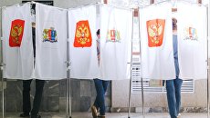 Избиратели в кабинках в единый день голосования на избирательном участке Избиратели в кабинках в единый день голосования на избирательном участке