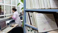 Медицинский работник выдает медицинскую карту пациенту в регистратуре районной поликлиники Медицинский работник выдает медицинскую карту пациенту в регистратуре районной поликлиники